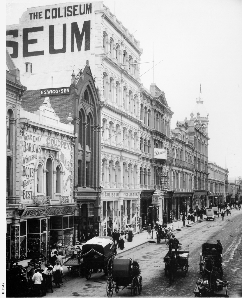 Rundle Street with shops, department stores and street traffic. Some of the shops from the extreme left are: Barlows Shoes; Coudrey's Chemist; E.S.Wigg & Son, Stationers; The Coliseum, Donaldson's and James Marshall department stores. People are patronising the street fruit and vegetable barrows and strolling past the shop windows. There is one motor car to be seen amongst the horse-drawn traffic (in front of Marshall's). [On back of photograph] 'Rundle street, looking east from King William Street / Nov. 1909 / Near side of Barlow's (on extreme left) is 30 yards east of King William St.'